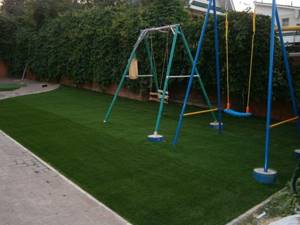 Children&#39;s swings on a playground with a sports lawn