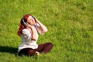 Girl in headphones on a meadow lawn
