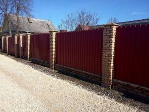 Fencing the site with a fence made of corrugated sheets on brick pillars