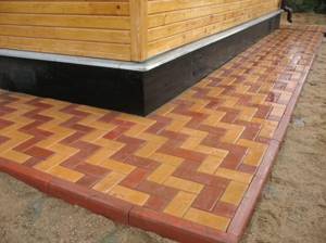 Blind area made of paving slabs around a wooden house
